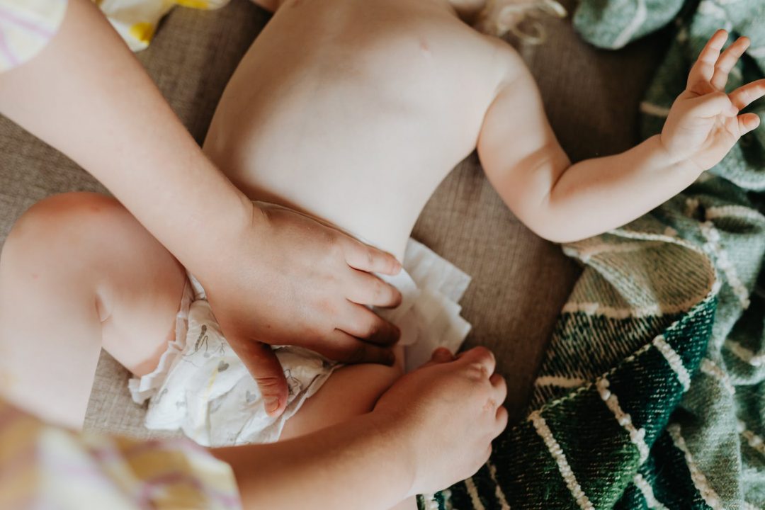 hands putting on diaper on baby