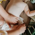 hands putting on diaper on baby